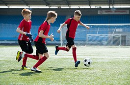 three boys playing soccer