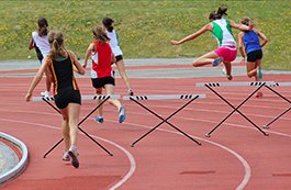 girls running track hurdles